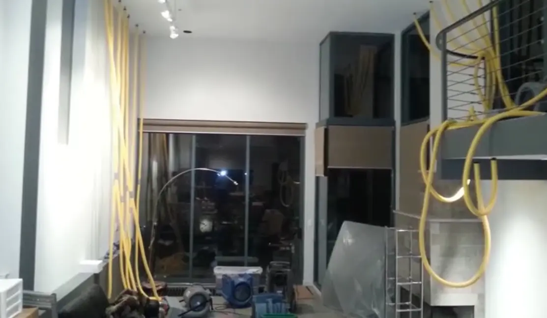 Technician using a moisture meter to detect hidden water damage behind a wall
